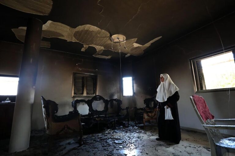 A Palestinian woman inspects a house burned during Israeli settlers' attack the day before in the town of Jit in Qalqilya, northern West Bank, on Aug. 16, 2024.