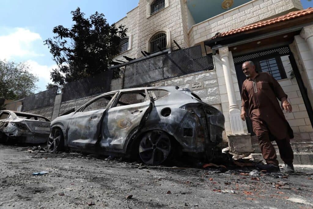 A Palestinian man walks past cars burned during Israeli settlers' attack the day before in the town of Jit in Qalqilya, northern West Bank, on Aug. 16, 2024.