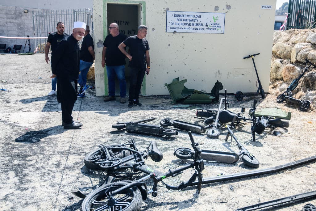 An Israeli Druze elder examines the charred remains of scooters next to the football field where the rocket strike happened. Israeli Druze mourners gathered for the funeral of 12 children and teens killed in a Hezbollah rocket strike at a soccer field in Majdal Shams, Golan Heights.