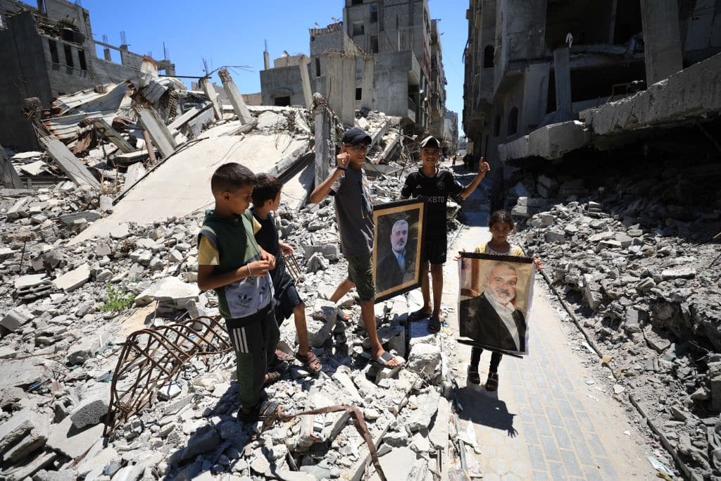 Palestinians carry the portrait of Hamas political bureau chief Ismail Haniyeh, who was assassinated, as they stand on the debris of destroyed building, belonged to Ismail Haniyeh, following the Israeli attack in Al-Shati refugee camp of Gaza City, Gaza on July 31, 2024.