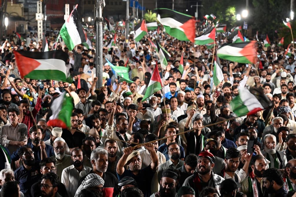 Activists and supporters of Pakistan's Jamaat-e-Islami (JI) party hold Palestinian flags as they attend an absentee funeral prayers for slain Hamas political leader Ismail Haniyeh, next to his poster in Rawalpindi on July 31, 2024, following his assassination in an air strike in Tehran.