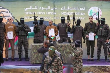 Hamas terrorists escort Israeli hostages (L-R, holding certificates) Ohad Ben Ami, Eli Sharabi and Or Levy on a stage before handing them over to a Red Cross team in Deir el-Balah, central Gaza, on February 8, 2025.