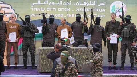 Hamas terrorists escort Israeli hostages (L-R, holding certificates) Ohad Ben Ami, Eli Sharabi and Or Levy on a stage before handing them over to a Red Cross team in Deir el-Balah, central Gaza, on February 8, 2025.