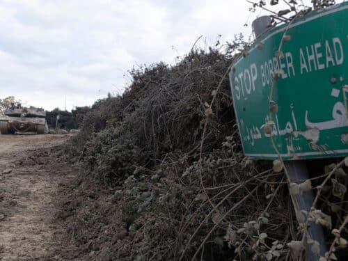 An Israeli tank is parked near a sign warning of the border with Lebanon on December 4, 2024 in Metula, Israel.