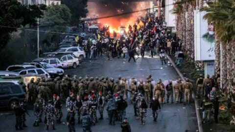 Fire from burning tires burns as supporters of Lebanese Shiite Islamist movement Hezbollah stand before Lebanese Army soldiers during a Hezbollah-organised rally to block the road to Beirut International Airport over a decision to bar two Iranian flights from landing there, in Beirut on February 15, 2025.