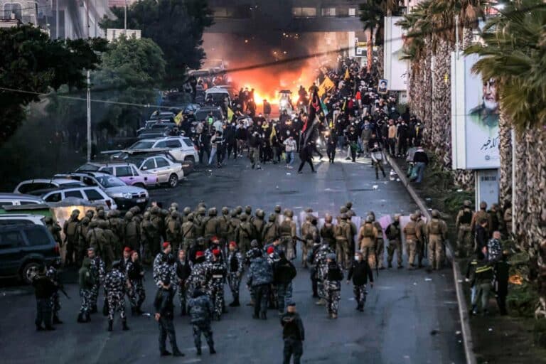 Fire from burning tires burns as supporters of Lebanese Shiite Islamist movement Hezbollah stand before Lebanese Army soldiers during a Hezbollah-organised rally to block the road to Beirut International Airport over a decision to bar two Iranian flights from landing there, in Beirut on February 15, 2025.